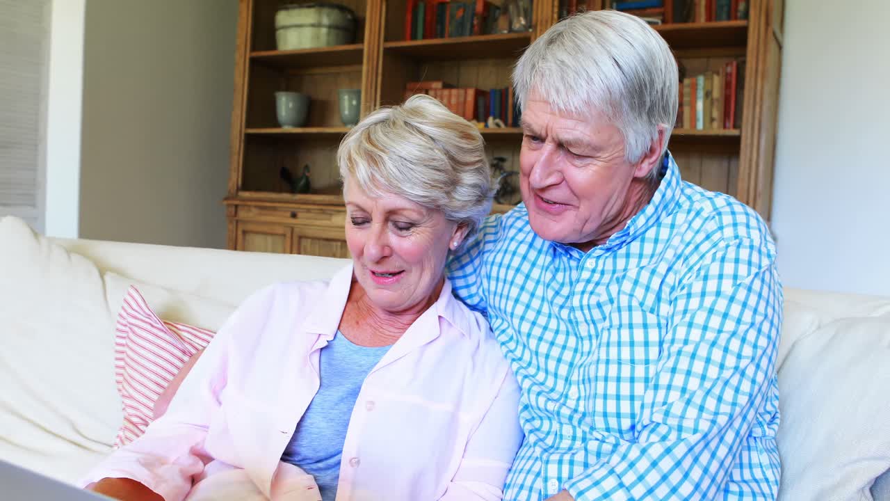 거실에서 노인 커플이 노트북을 사용하고 있습니다.