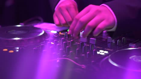 hands of dj moving controls on record deck in night club, up close