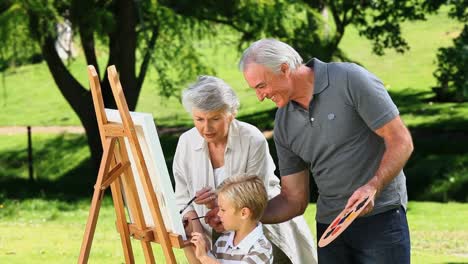 Young-boy-painting-a-canvas-with-grandparents