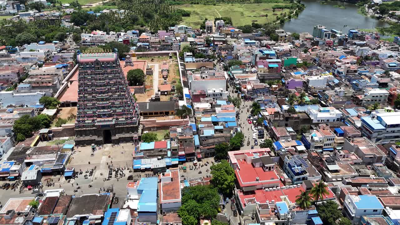 Beautiful aerial footage of Tenkasi’s Kasi Viswanathar Temple complex surrounded by colorful town structures and vast green fields on a bright sunny day in South India
