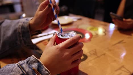 hand inserting straw into cola can