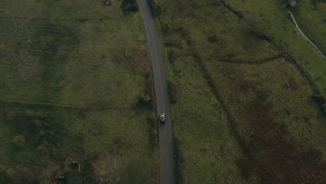 aerial drone shot following a car as it drives on a country lane