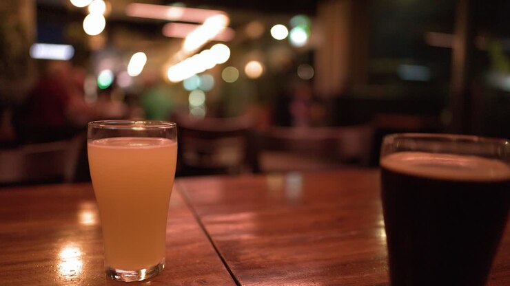 Inquadratura statica di bicchieri di birra chiara e birra scura stout su un tavolo da bar