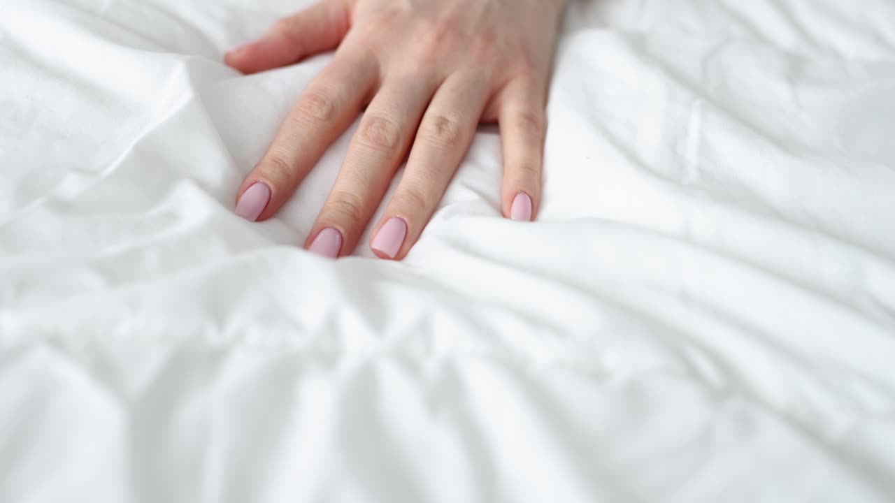 Hand on white bed sheet