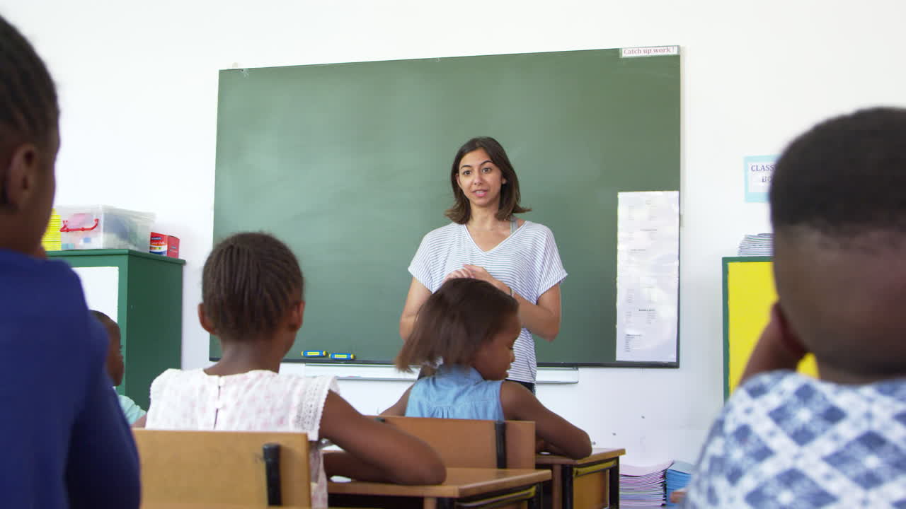 un maestro preguntando a los niños de la escuela primaria una pregunta en la clase