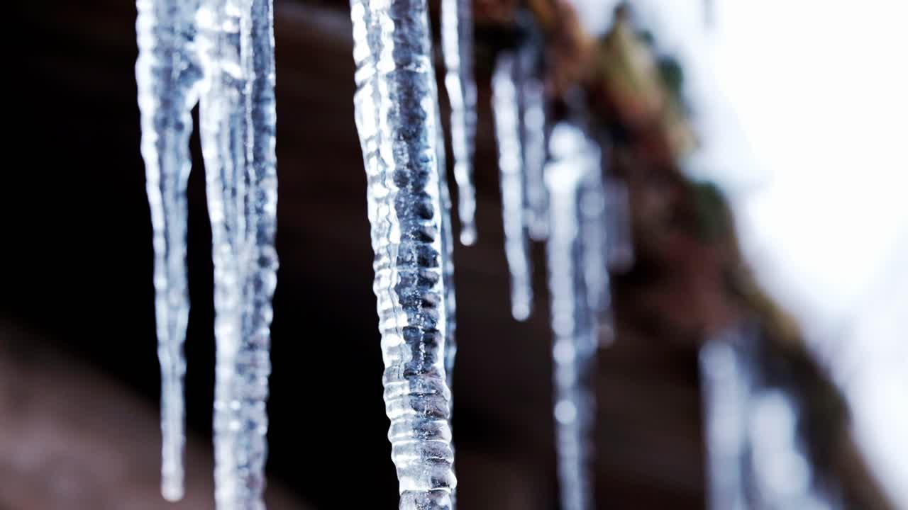 Wunderschöne Eiszapfen, die wie Kristalle aussehen und sich im Winter an einer Holzhütte gebildet haben.