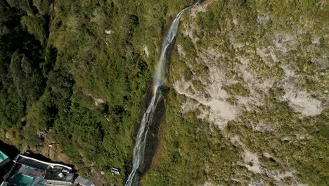 cascada de la virgen que fluye hacia abajo en un exuberante acantilado en baños de agua santa, ecuador - tiro de drone