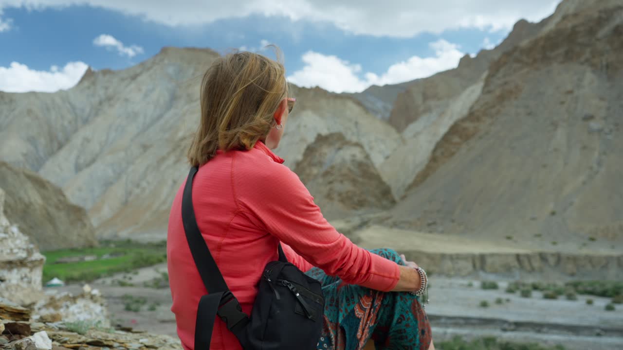 Turista de aventura aposentado sentado em uma cordilheira admirando as vistas das montanhas do Vale de Markha