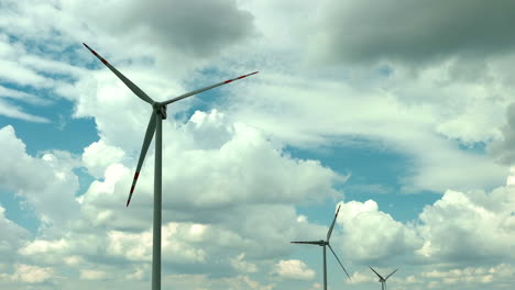 Aerial-footage-featuring-wind-turbines-set-against-a-backdrop-of-fluffy-clouds-and-a-blue-sky