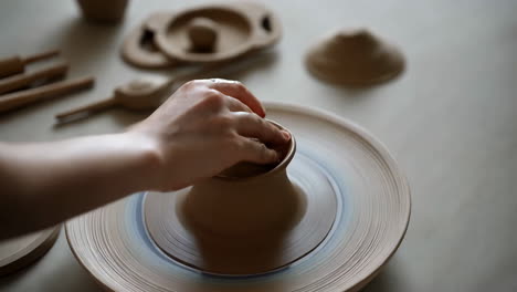 vrouw die klei vormt op een pottenbakkerswiel
