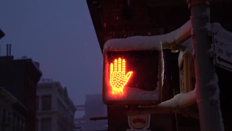 Pedestrian-traffic-light-turns-from-stop-to-walk-during-snowy-morning-in-Soho,-Manhattan,-New-York