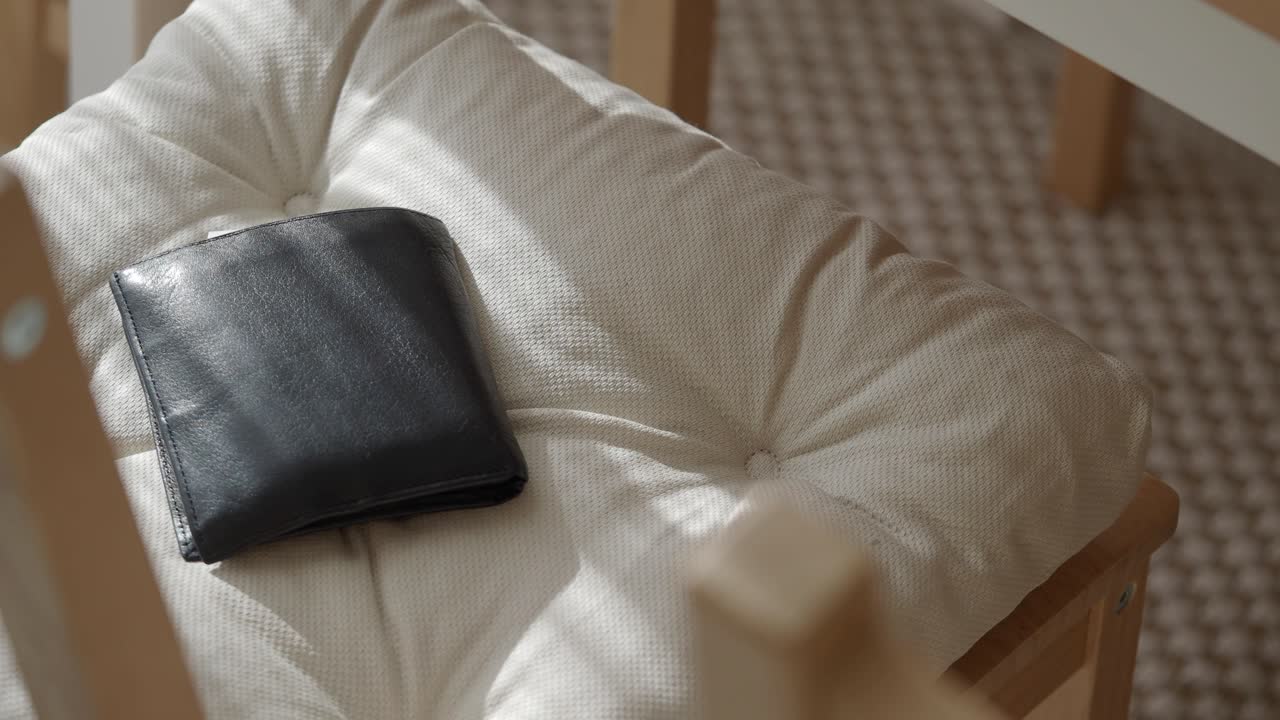 Black Wallet on a Cream Cushion in Sunlight
