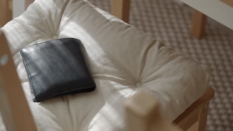 black wallet on a cream cushion in sunlight