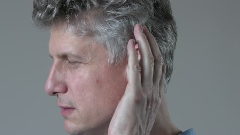 mature man cupping ear as he struggles to hear conversation