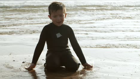 happy boy playing with water on sea coast