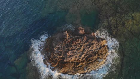 Waves-hitting-rocks-against-tiny-island-in-ocean