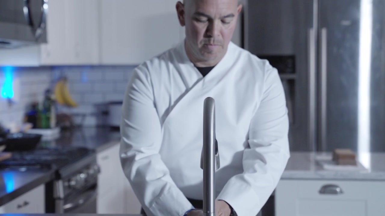 Ripresa ascendente di uno chef che entra in cucina e si lava le mani, sottolineando l'igiene in cucina e la preparazione per la cottura. Ideale per contenuti culinari incentrati sulla pulizia e la sicurezza alimentare