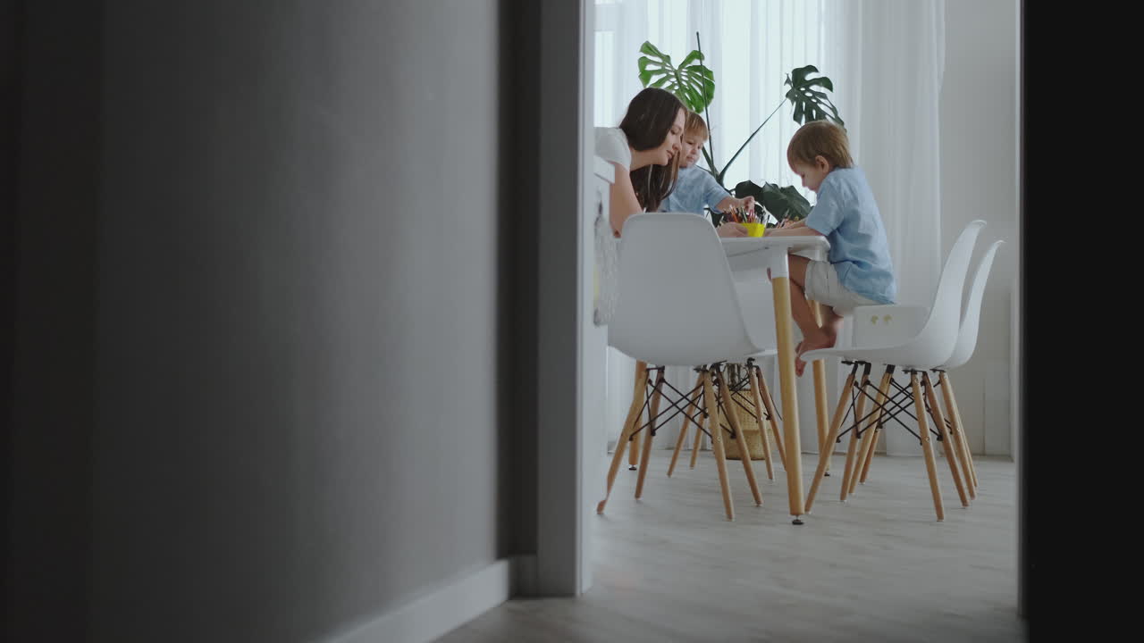 엄마 는 아들 들 이 그림 을 그리는 것 을 배우도록 도와줍니다. 가정 과제 를 하고 집 에서 유치원 준비 를 하고  ⁇ 색 주방 에 앉아 있습니다. 두 형제 는 함께 엄마 의 초상화 를 그립니다.