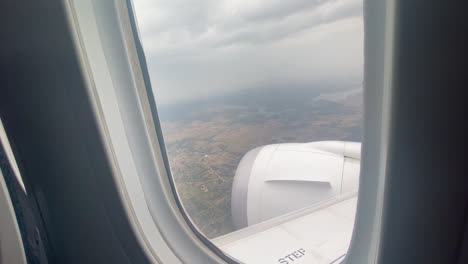 shot of the sky and the city from the window inside the cabin of an airplane flying on the way