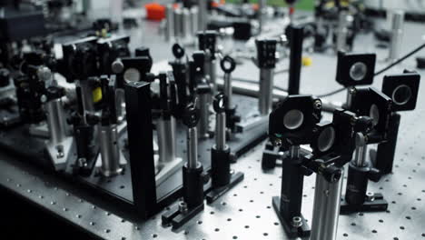 panorámica horizontal sobre una mesa óptica con diferentes elementos láser y espejo para mediciones científicas precisas