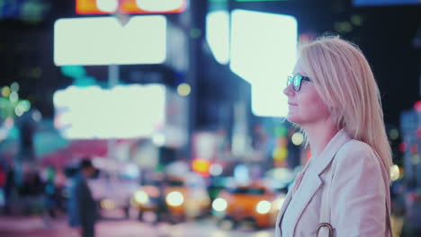 attractive woman admiring the lights of the famous time square in new york yellow cabs passing by -