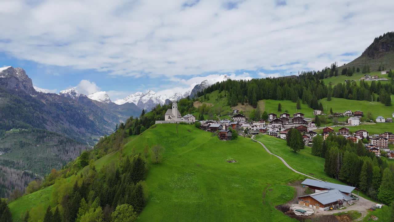Aerial view of Selva di Cadore village surrounded by green hills and the dramatic Dolomite mountains