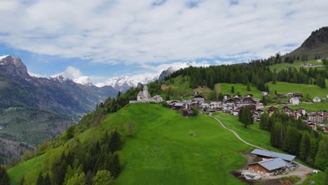Aerial view of Selva di Cadore village surrounded by green hills and the dramatic Dolomite mountains