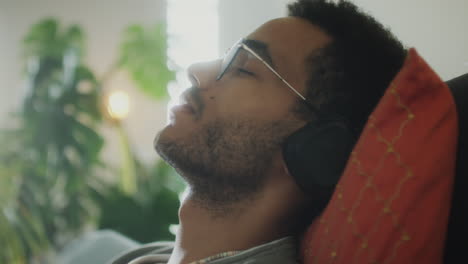 relaxed man in headphones enjoying music on sofa