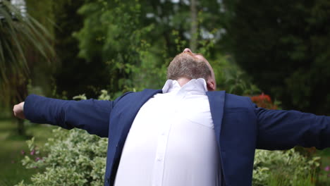 a happy businessman relaxing in a garden surrounded by flowers, plants and trees