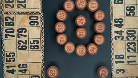 creative close-up smooth zoom out tiro giratorio desde arriba de un bingo barriles de madera en un círculo, figuras de madera, viejos números de fondo, juego de mesa vintage, iluminación profesional, cámara lenta 120 fps