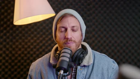podcast or radio host in live streaming session listening and nodding to camera. guest speaking while cool hipster man in professional sound studio is waiting. agreeing and smiling. portrait of male