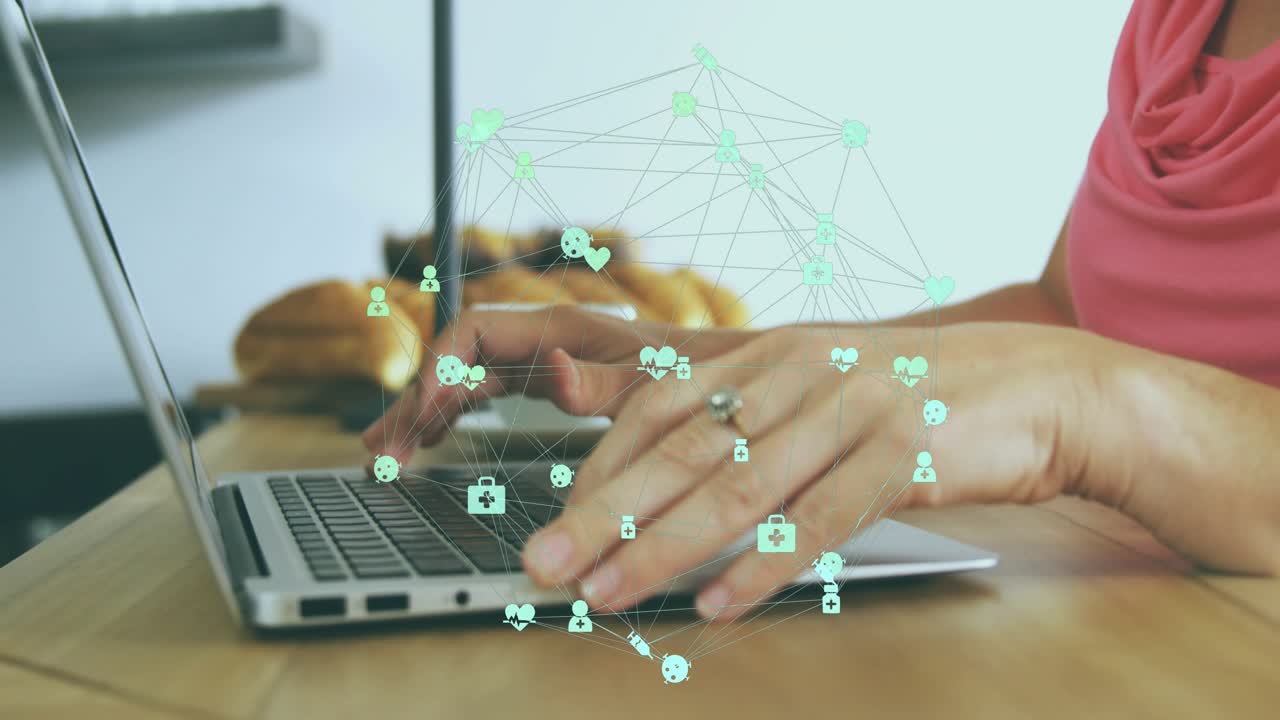 Woman's hands typing on silver laptop activating health icons forming network for visualization
