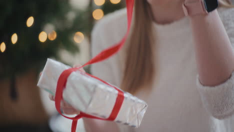 happy woman opening wrapped christmas present at home