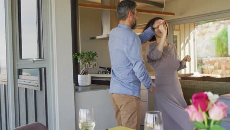 Happy-diverse-couple-smiling-and-dancing-together-in-dining-room