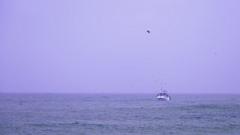 pequeño barco de pesca en el océano atlántico durante un día lluvioso, frío y ventoso, toma en cámara lenta con gaviotas volando cerca del buque