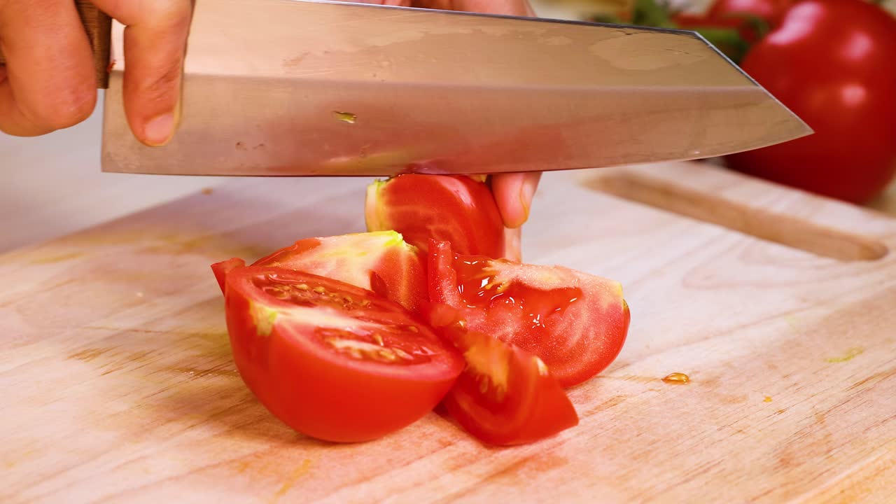 요리사는 능숙하게 토마토를 조각으로 잘라니다.
