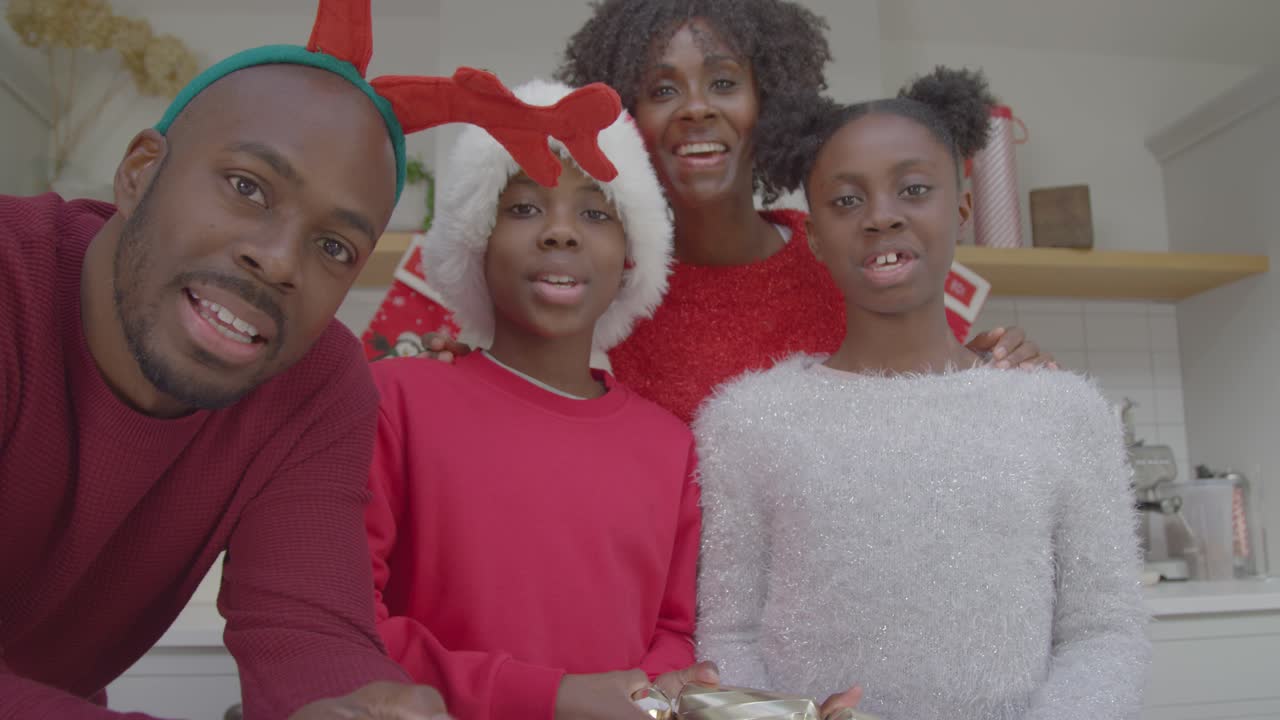 familia alegre saludando y tirando galletas navideñas durante la videollamada navideña