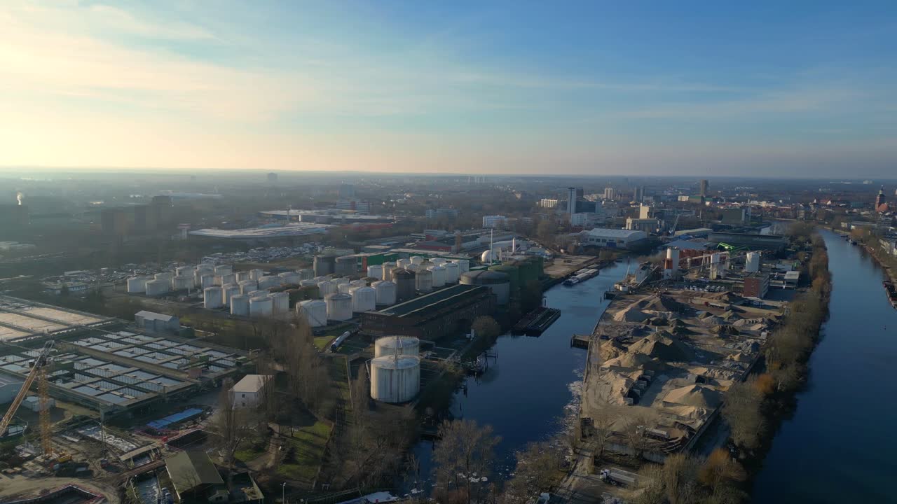 large industrial power plant emitting large amounts of smoke over the city Berlin next to a river on a sunny day. Unbelievable aerial view flight rotation to right drone