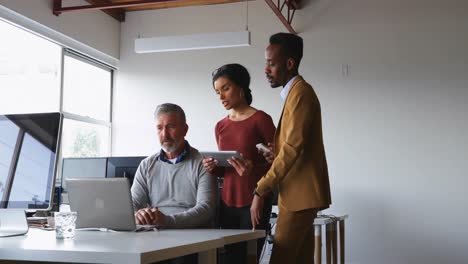 Executives-discussing-over-laptop-at-desk-4k