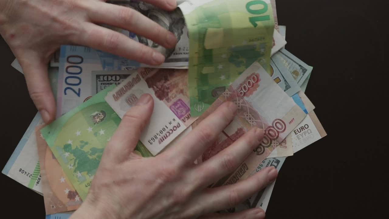 руки хватают сбор валютных банкнот с черного стола доллары, евро, рубли