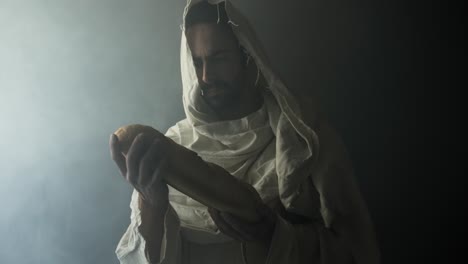 jesus christ in white robe holding bread as he stands in glowing, bright light. perfect for representation of jesus as the bread of life, last supper, communion, the gospel, christian sacraments.