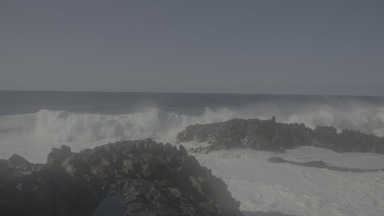 강력한 파도가 바위가 있는 해안에 부히고
