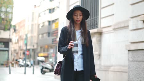 Hispanic-woman-with-takeaway-coffee-and-smartphone