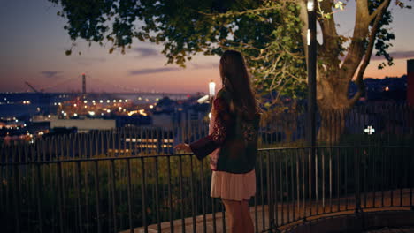 woman looking night cityscape standing at railings. girl enjoying twilight sky
