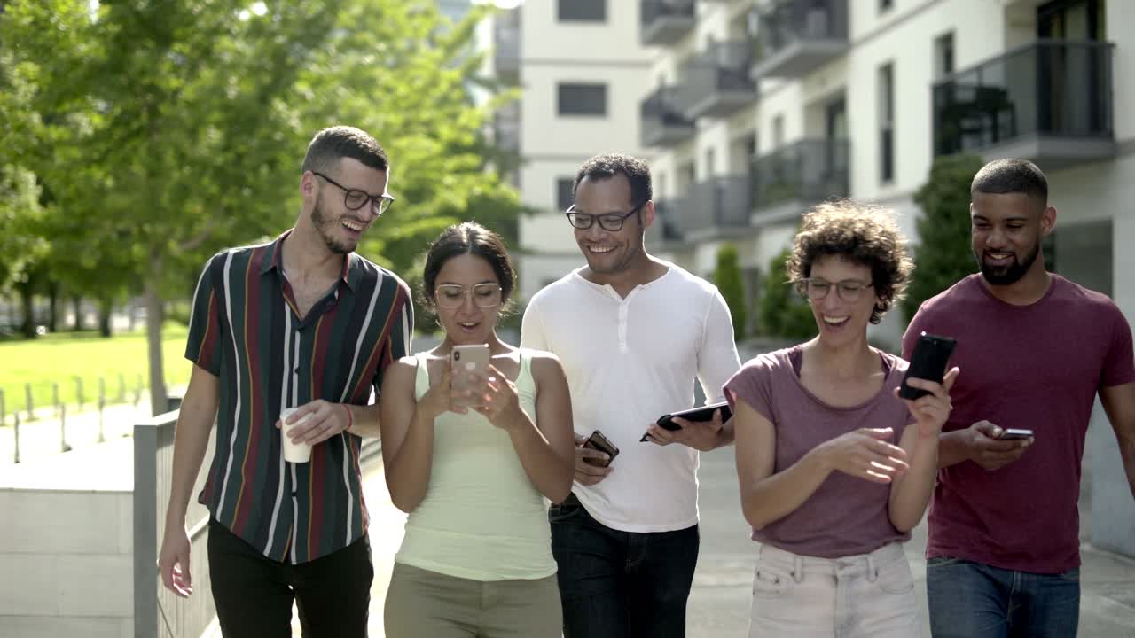 amigos felices con teléfonos inteligentes caminando por la calle.