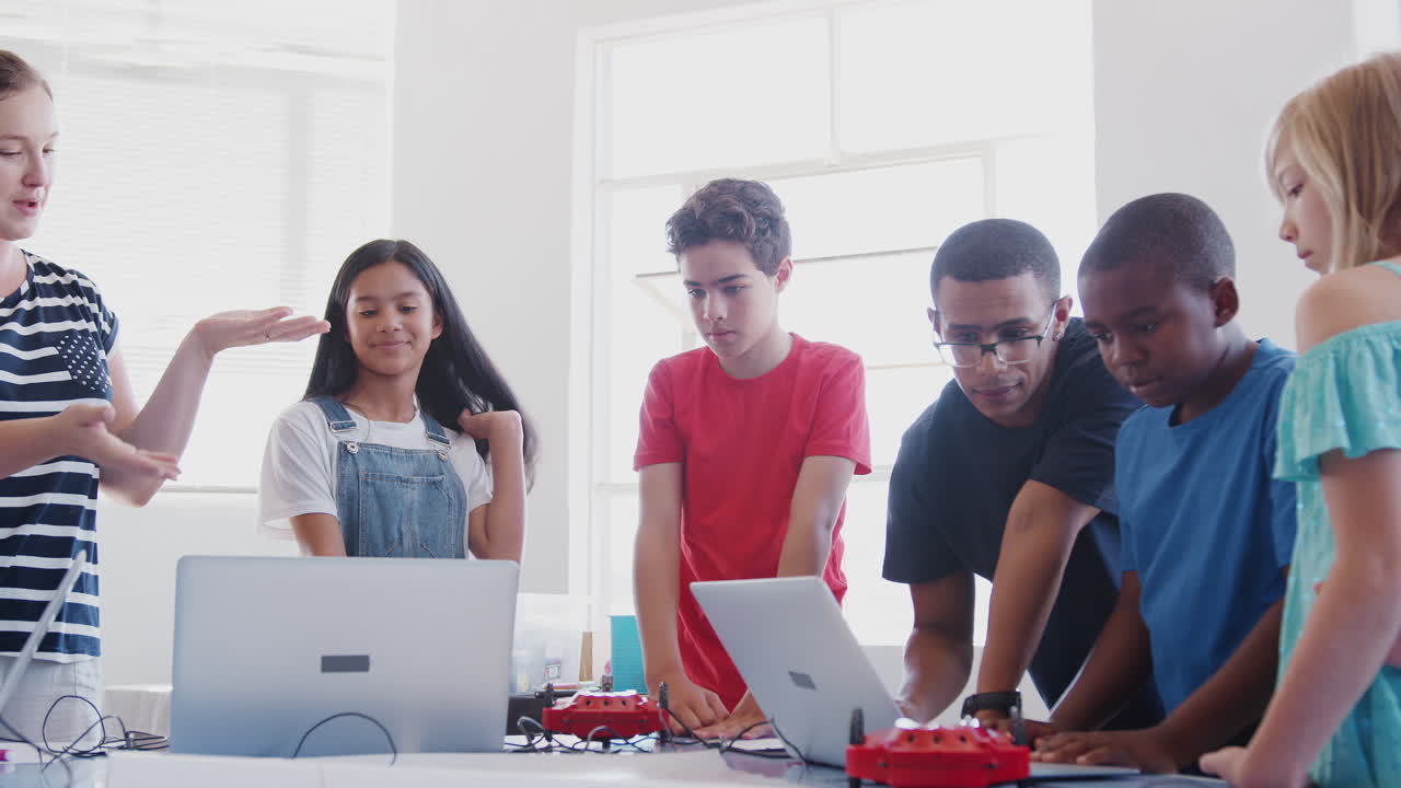 étudiants avec des enseignants en cours de codage informatique après l'école apprenant à programmer un véhicule robot