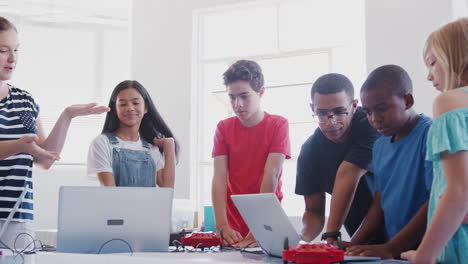 estudiantes con maestros en clases de codificación de computadoras después de la escuela aprendiendo a programar vehículos robóticos
