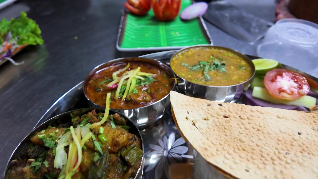 Primer plano de una bandeja thali de acero inoxidable con dal, papadum y naan en Bangkok