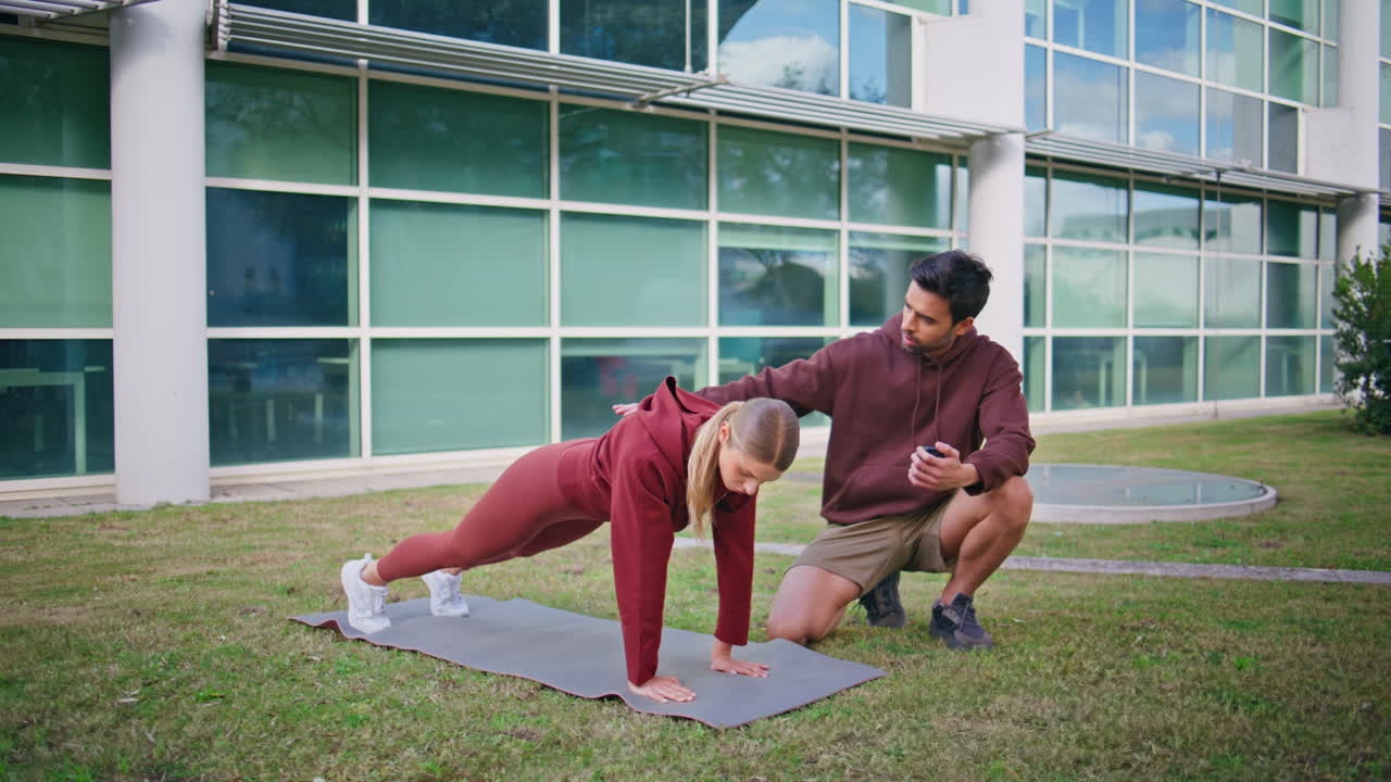 Fitness coach instructing woman in plank position. Focused athlete doing abs