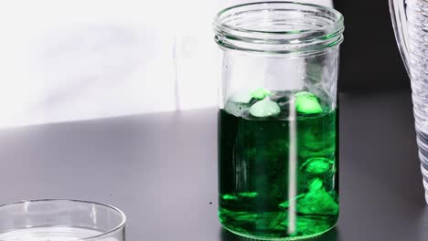 observe dry ice reacting in a jar of green liquid, creating a smoky effect.